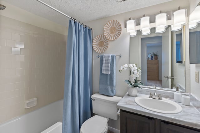 Bathroom with a blue shower curtain, toilet, sink, and vanity.