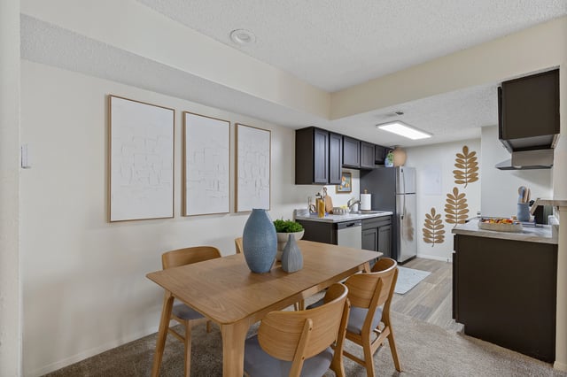 Dining area and kitchen with dark cabinets, stainless steel appliances, and a wooden dining table.