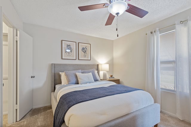 Cozy bedroom with a king-sized bed, nightstand, and ceiling fan.
