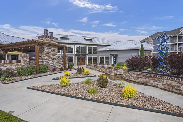 Modern apartment building exterior with a courtyard and sculpture.