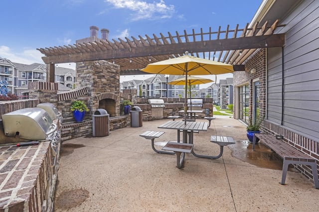 Outdoor grilling area with grills, picnic tables, and a fireplace.