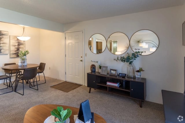 Living room with a dining table and chairs, a console table with decorative items, and a doorway.