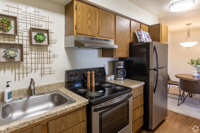 Kitchen with stainless steel appliances, wooden cabinets, and granite countertops.
