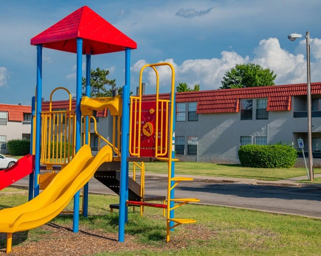 Playground with slides and swings in front of apartment buildings.