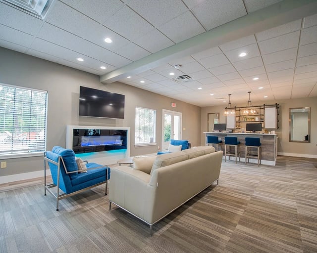 Lobby with modern fireplace, large TV, and a front desk with bar stools.