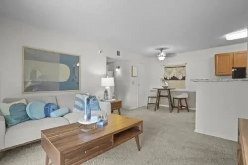 Living room and open kitchen in an apartment unit with a sofa, coffee table, and bar stools.