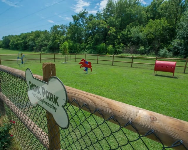 Fenced grassy dog park area with Bark Park sign