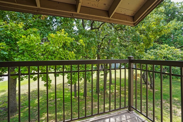 View from balcony overlooking a grassy area with trees.