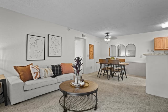Cozy living and dining area with a gray sofa, coffee table, and wooden dining set.