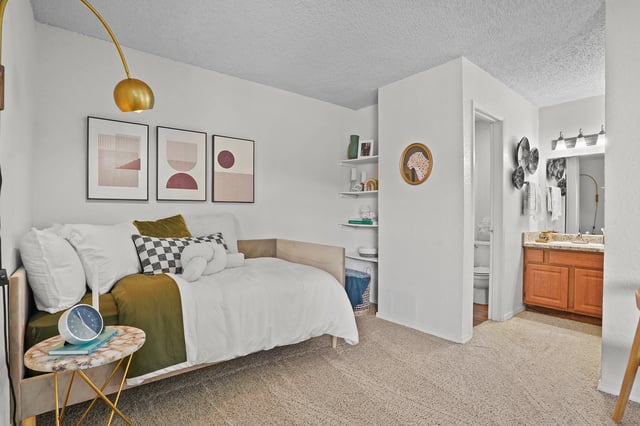 Stylish bedroom with a daybed, abstract art, and a glimpse of the bathroom vanity.