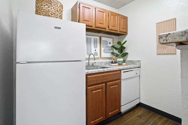 Kitchen with a white refrigerator, wooden cabinets, and a dishwasher.