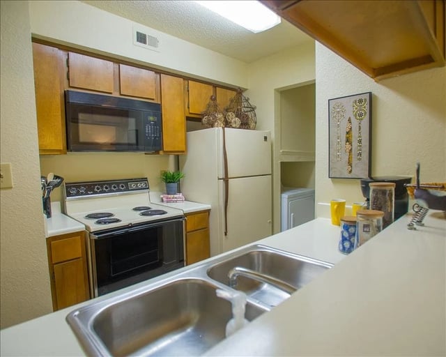 Kitchen with white appliances, wooden cabinets, and a double sink.