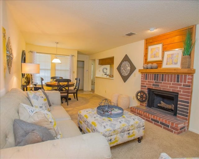 Living room with a fireplace, couch, and dining area.