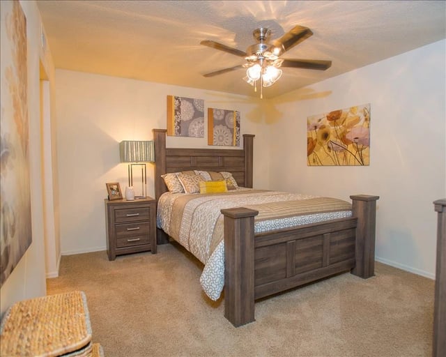 Bedroom with a queen-size bed, nightstand, and ceiling fan.