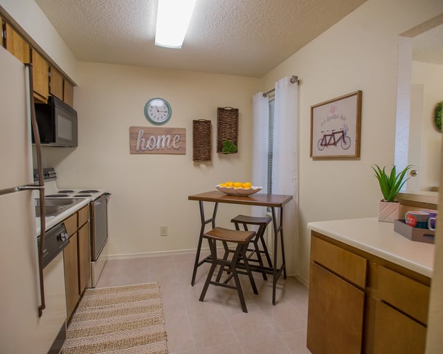 Kitchen area with a table and chairs, refrigerator, oven, and sink.