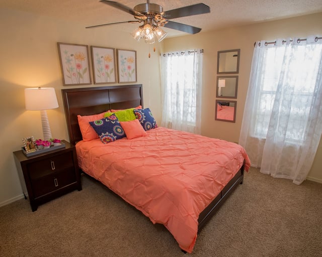 Bedroom with a queen-sized bed, nightstand, and ceiling fan.