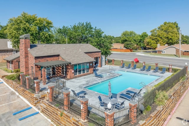 Outdoor swimming pool with lounge chairs and seating areas next to a clubhouse.