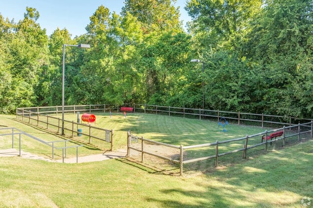 Fenced-in dog park with agility equipment, benches, and a tunnel.
