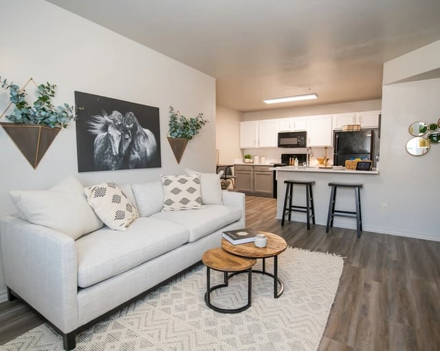 Bright living room with a white sofa, coffee table, and open-concept kitchen.