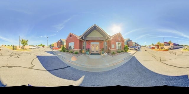 Exterior view of apartment building entrance and surrounding parking lot.