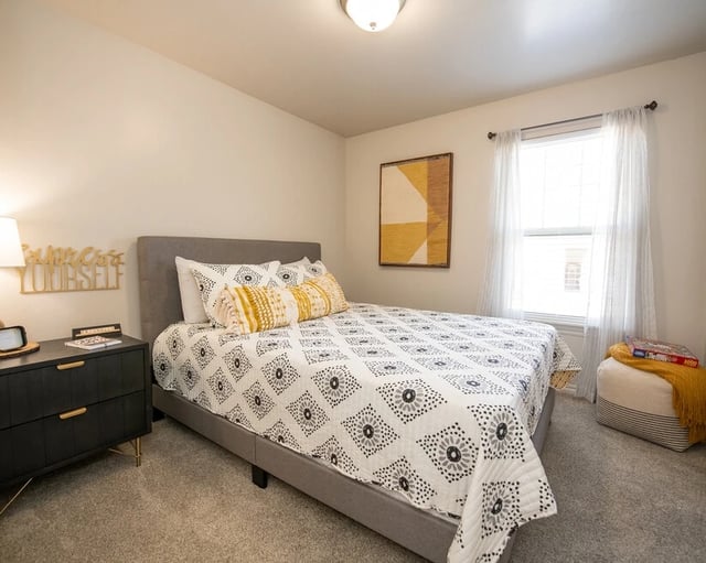 Bedroom with a queen-sized bed, nightstand, and window.