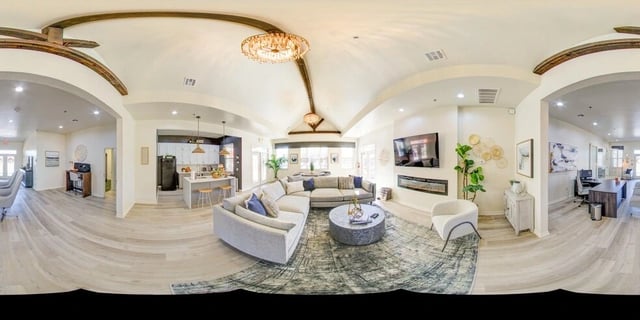 Spacious open-concept living area with a large sectional sofa, coffee table, fireplace, and a view of the kitchen.