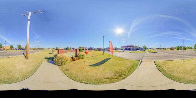 Monument sign for "The Cross Timbers" with a brick base and landscaping, alongside a street with apartment buildings in the background.