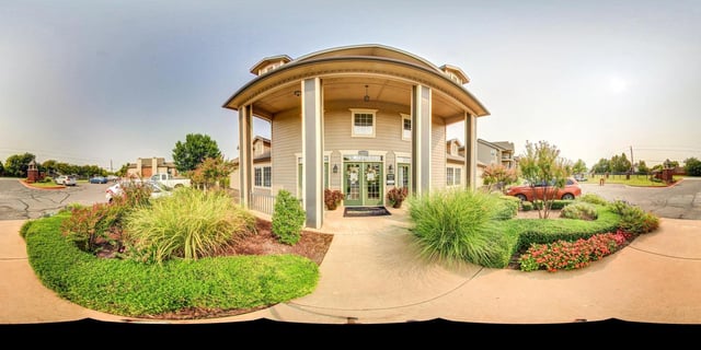 Exterior entrance to apartment buildings with landscaping and parking.