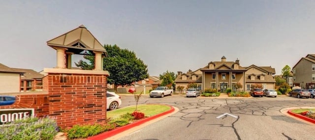 Apartment complex entrance with brick monument sign and building exteriors.