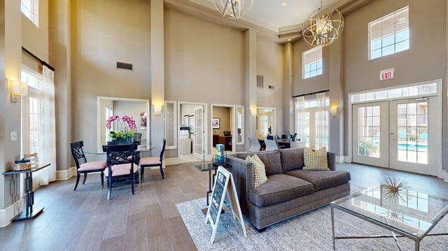Interior lounge area with seating, a dining table, and view of the pool through glass doors.