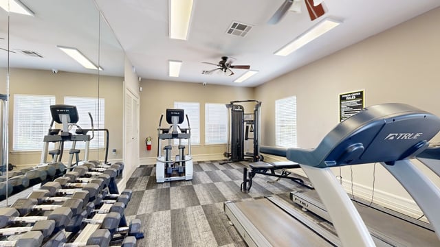 Fitness center with treadmills, elliptical, weight rack, and multi-station gym.