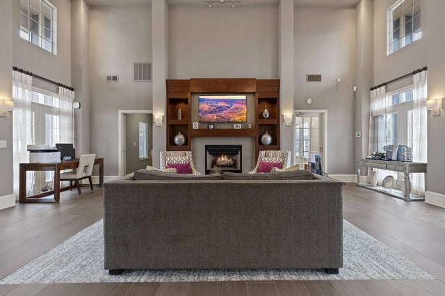 Spacious resident lounge with fireplace, seating area, and workstations.