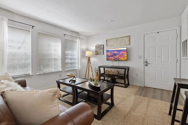 Living room with brown leather sofa, coffee tables, and a mounted TV.