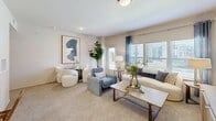 Spacious living room with large windows, comfortable seating, and modern decor.