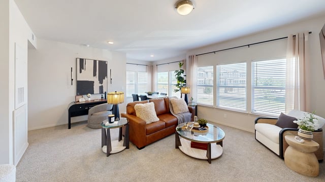 Living room with a brown leather sofa, accent chair, coffee table, and dining table.