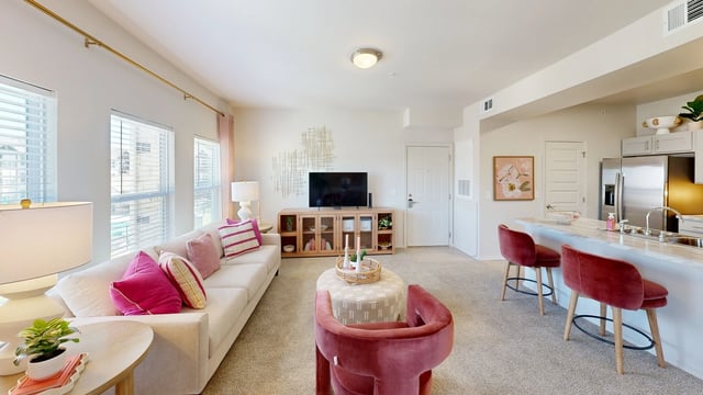Living room and kitchen area with island seating in a modern apartment.