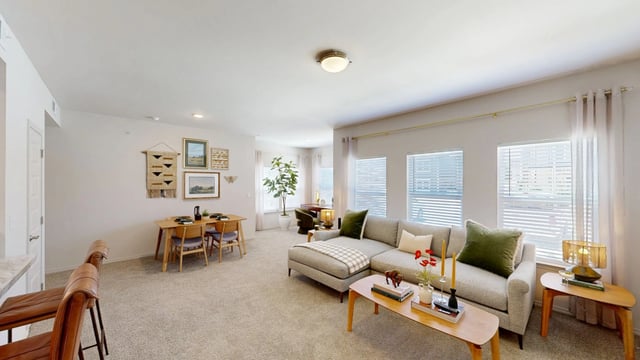 Living room and dining area in apartment with sectional sofa, dining table, and desk.