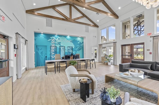 Interior lobby with seating area, reception desk, large windows, and teal accent wall.