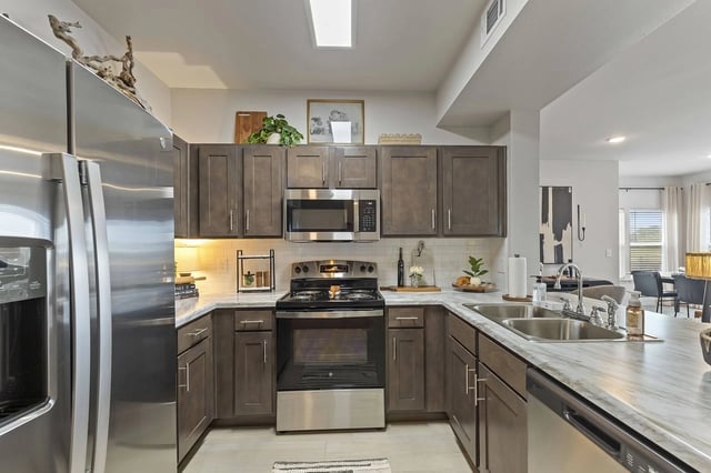 Modern kitchen with dark wood cabinets and stainless steel appliances including a double sink.