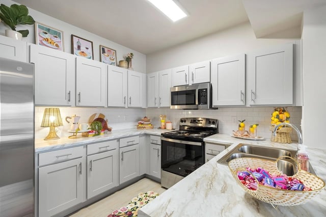 Modern kitchen with gray cabinetry, stainless-steel appliances, and marble countertops.