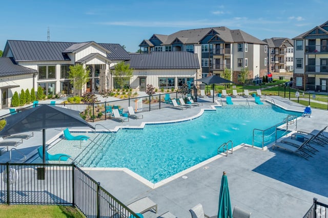Large outdoor swimming pool with lounge chairs and umbrellas.