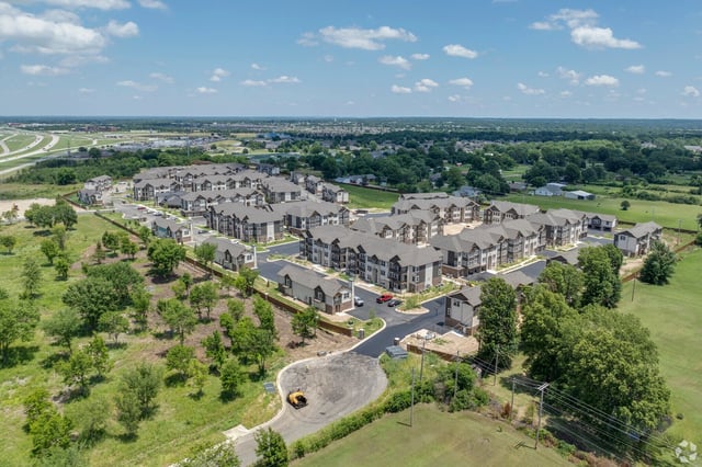 Aerial view of a modern apartment complex with multiple buildings and surrounding green space.