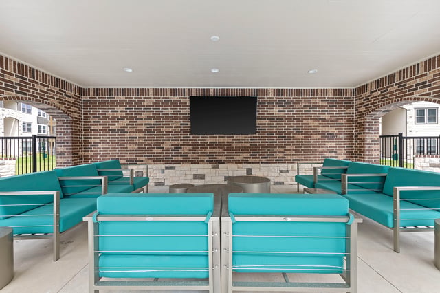 Outdoor covered lounge area with teal sofas and modern metal furniture.