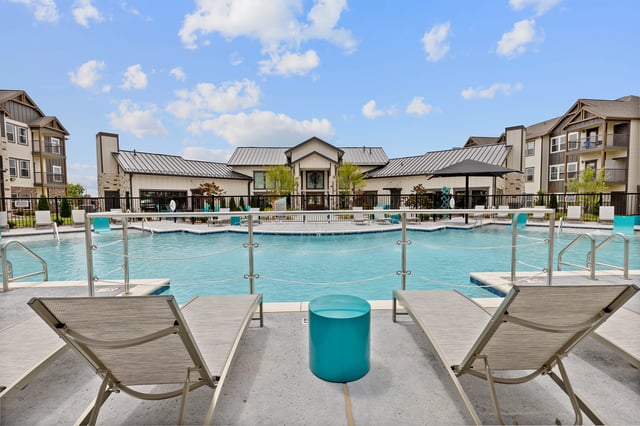 Swimming pool and lounge chairs with apartment buildings in the background.
