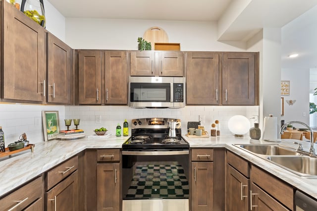 Modern kitchen with dark wood cabinets, white subway tile backsplash, and stainless steel appliances.