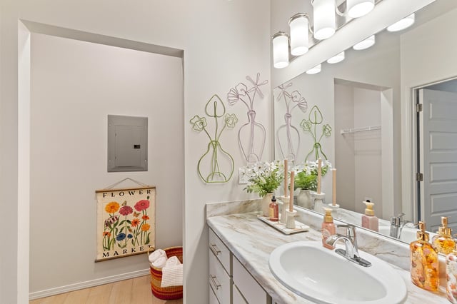 Modern bathroom with a single vanity and a large mirror reflecting a light fixture and wall decor.
