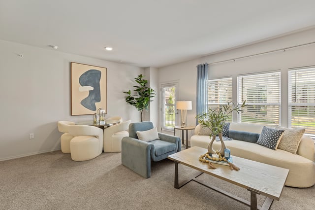 Living room with a sofa, chairs, coffee table, dining table, and artwork.