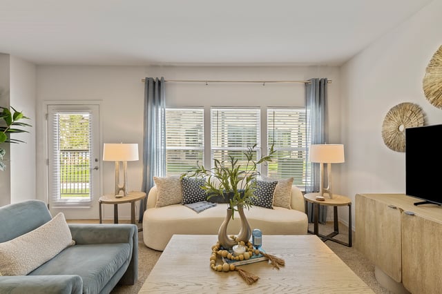 Living room with a curved sofa, coffee table, and large windows.