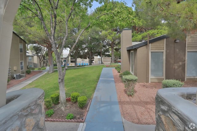 Path to leasing center with landscaping and apartment buildings.