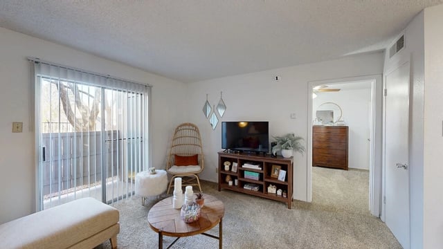 Living room with a TV, chair, coffee table, and a doorway to a bedroom.